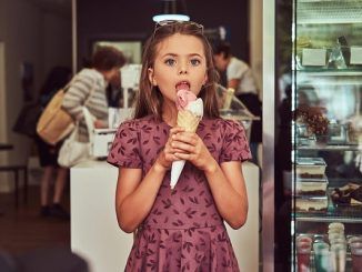 Beauty girl in fashionable dress eating strawberry, standing in ice cream shop. Top 3 best ice cream parlors in Mexico City