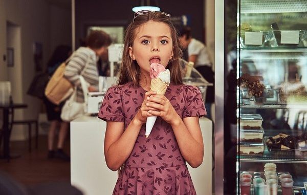 Beauty girl in fashionable dress eating strawberry, standing in ice cream shop. Top 3 best ice cream parlors in Mexico City