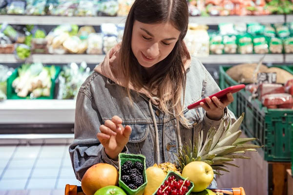 Young woman buys food in supermarket phone hand