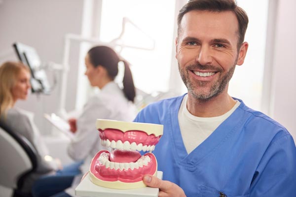smiling-dentist-showing-artificial-denture